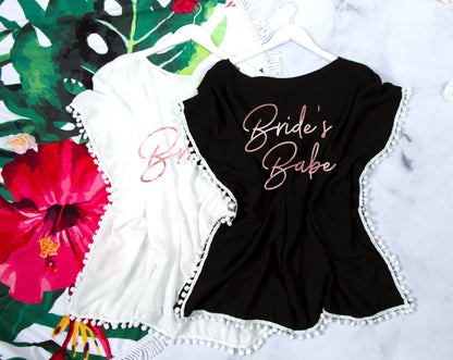 Three cover-ups flat-laid on a tropical floral backdrop, "Bride's Babe" printed in rose gold