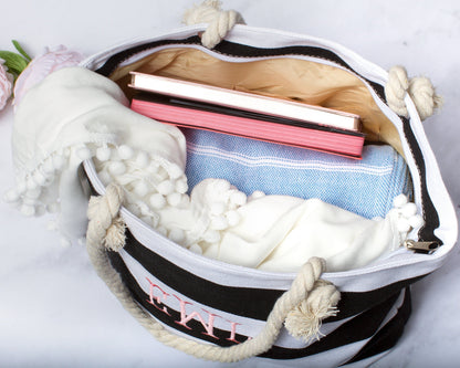 The beach tote open and packed with books, a folded towel and clothing, showing how much it holds