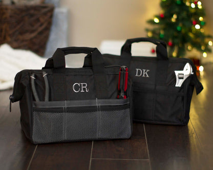 Two personalized tool bags monogrammed CR and DK standing side by side on a wood floor