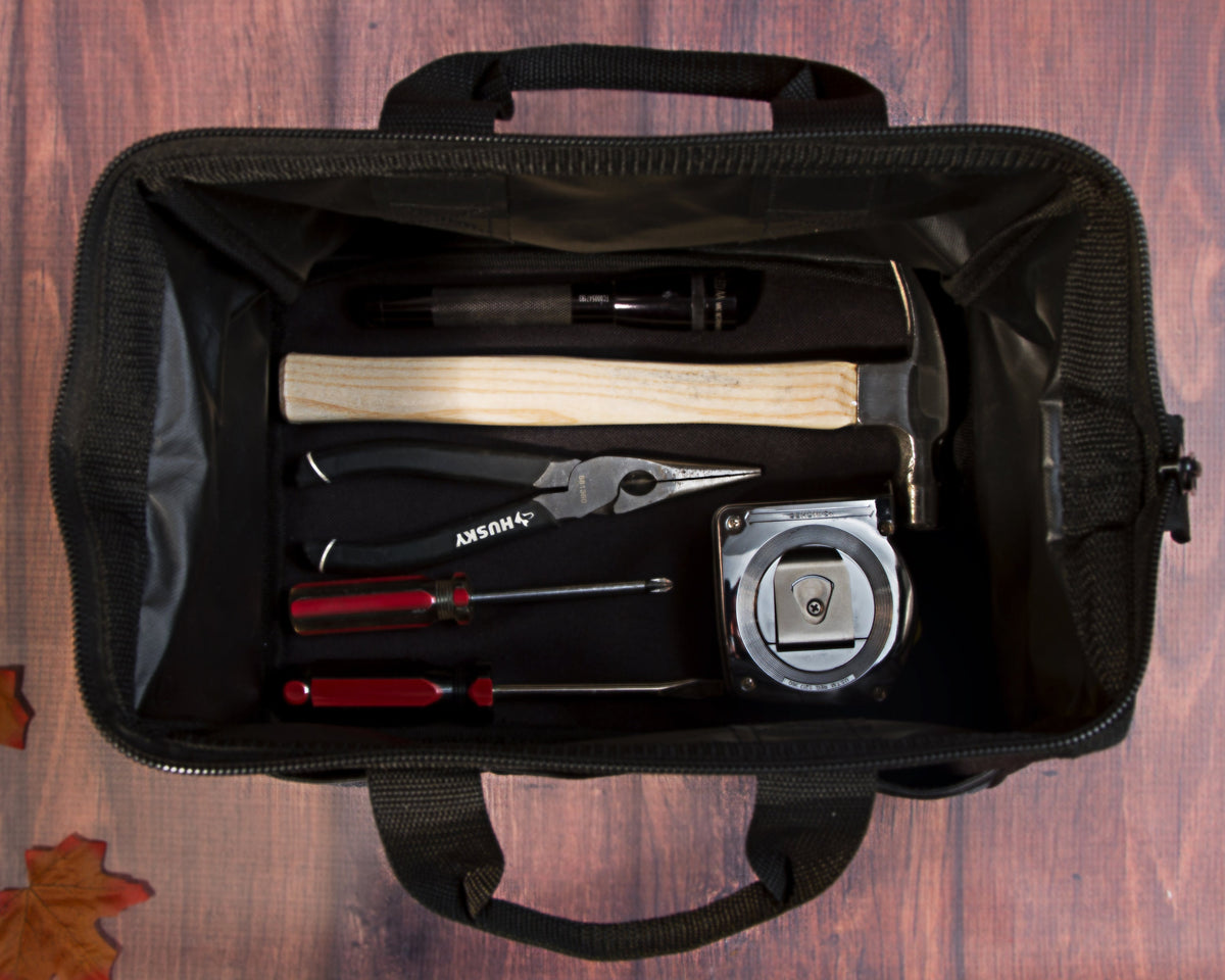 Open tool bag seen from above holding a hammer, pliers, screwdrivers and a tape measure