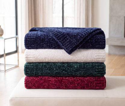 Folded Stargazer chenille throws stacked in Starfall navy, Moonstone cream, Aurora deep green, and Nebula burgundy.