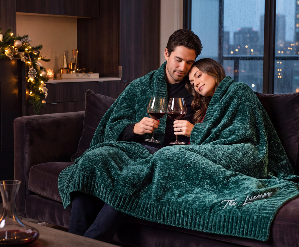 Aurora deep green Stargazer chenille throw shared on a sofa, with The Luceros embroidered in the corner.