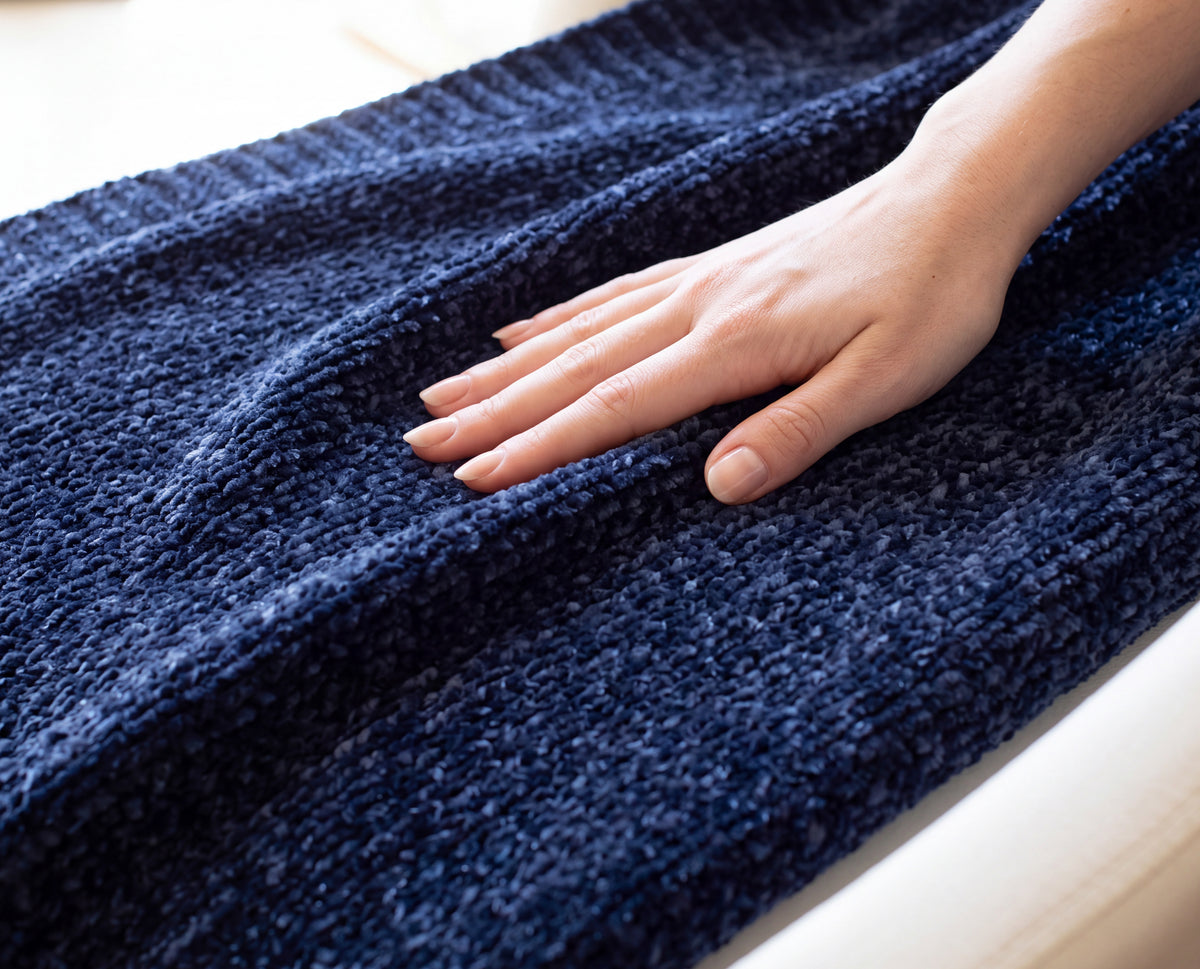 Close-up of a hand resting on the plush chenille texture of the Starfall navy Stargazer throw.