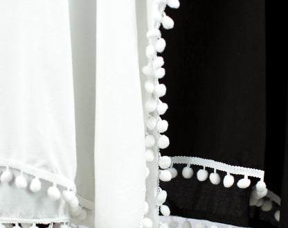 Close-up of the white pom-pom trim on the white and black cover-ups