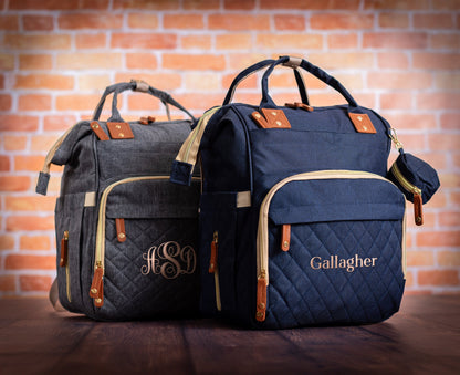 The Nursery Run Diaper Backpack — navy and gray, personalized with a monogram and a family name