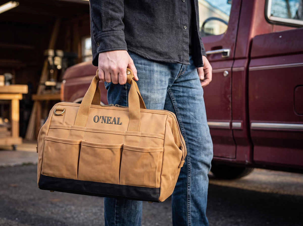 Person carrying a Brown canvas tool bag by its top handles.