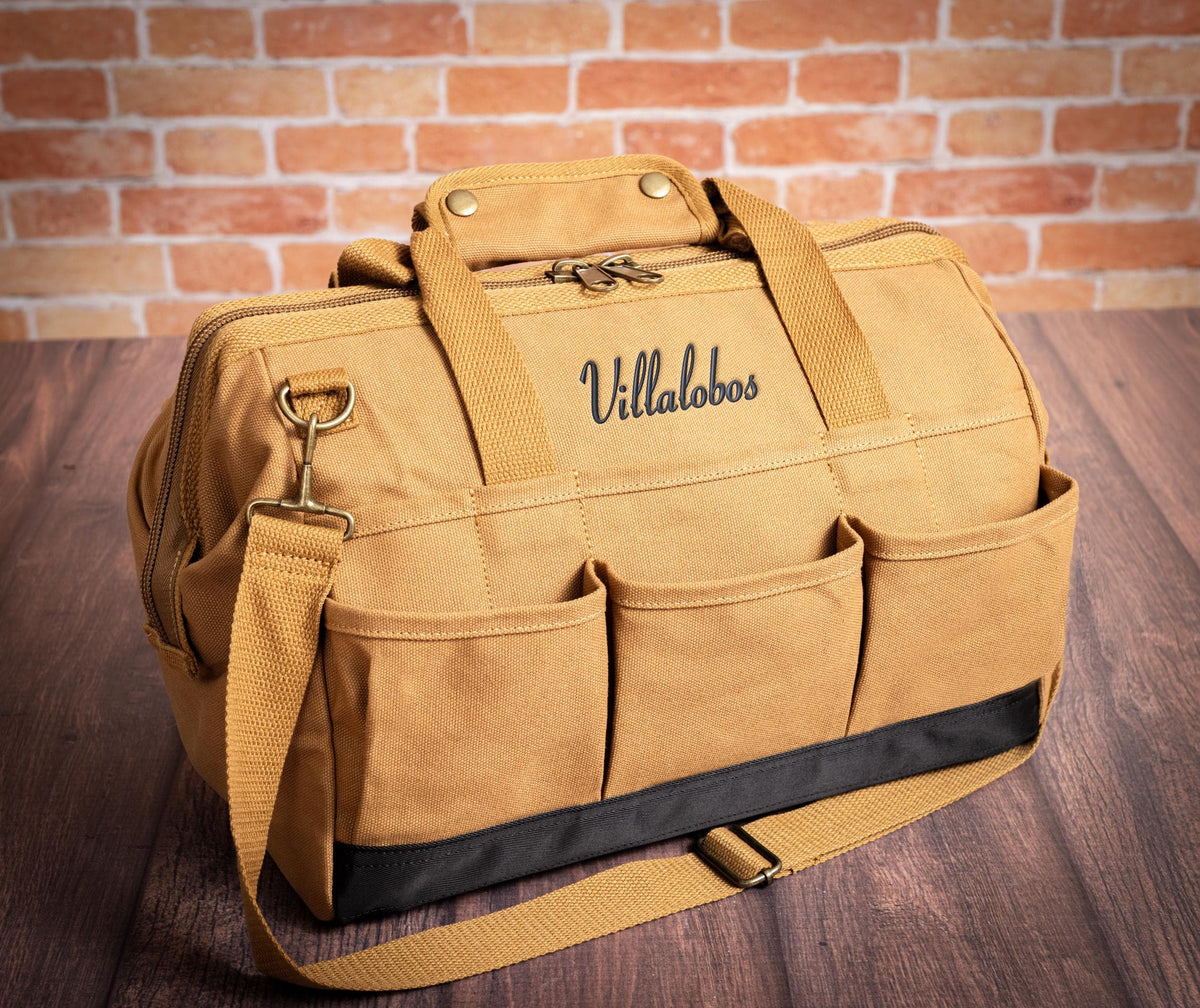 Close view of Brown canvas tool-bag handles, stitching and zipper.