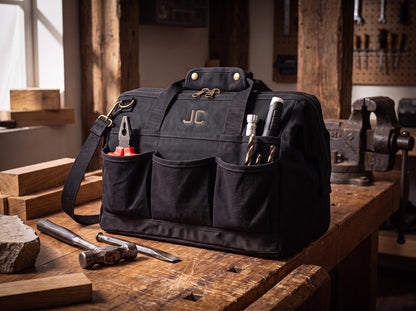 Black canvas tool bag with top handles, detachable shoulder strap and brass-tone fittings.